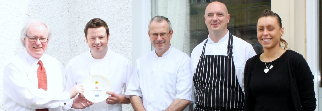 Five members of Mackays Hotel staff standing in a line outside in the sun