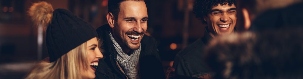 A group of friends in winter wrapped up warm and laughing