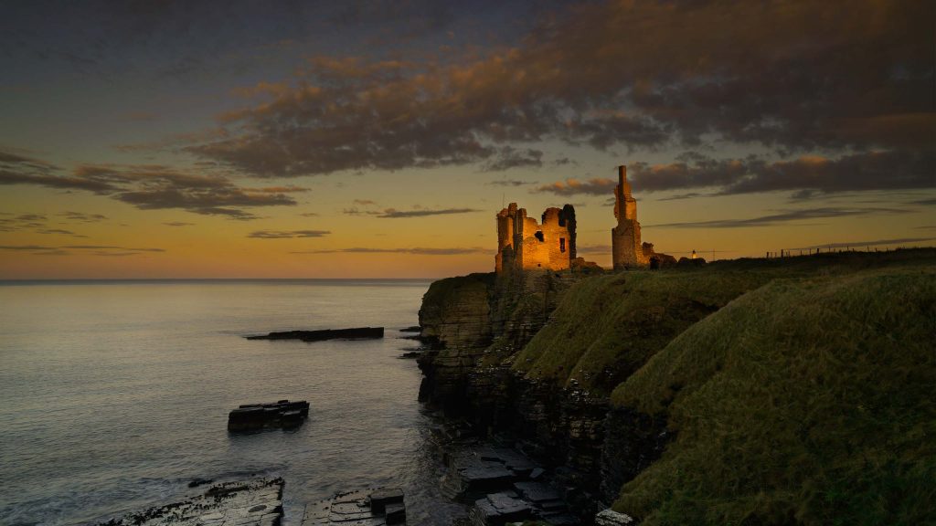 Castle Sinclair Girnigoe on top of the cliffs lit up at night in Caithness