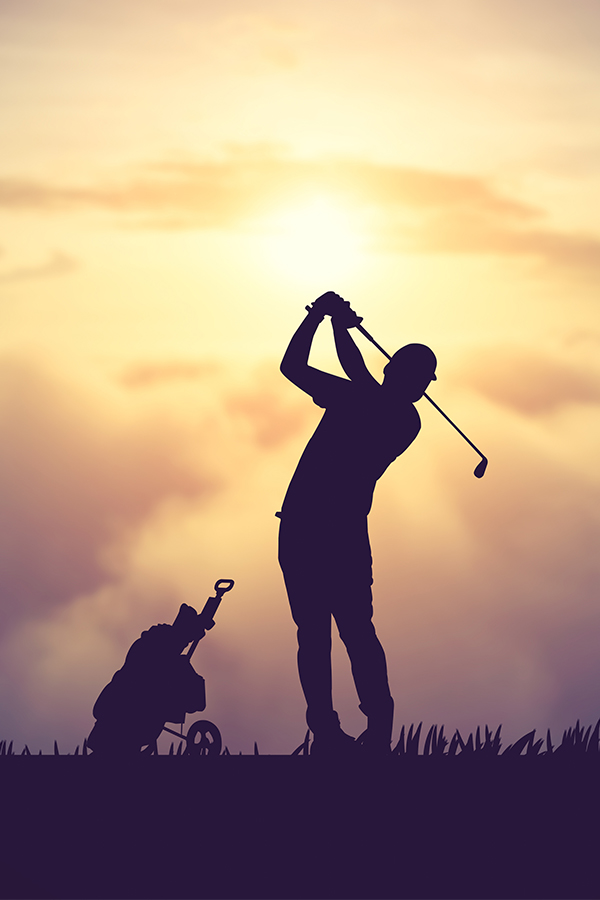 A silhouette of a golfer taking a swing at sunset