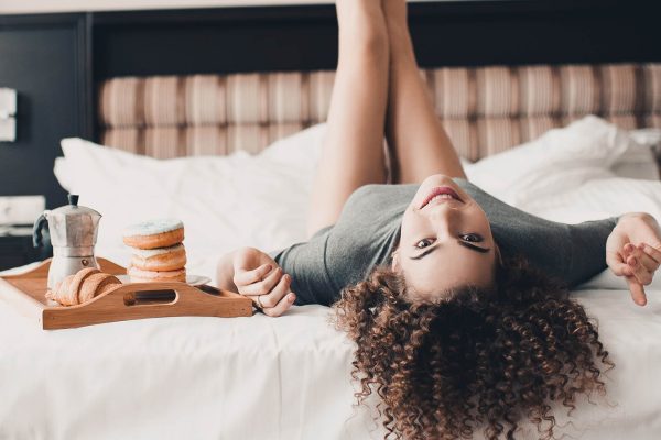 A girl lying on a hotel bed with her legs in the air