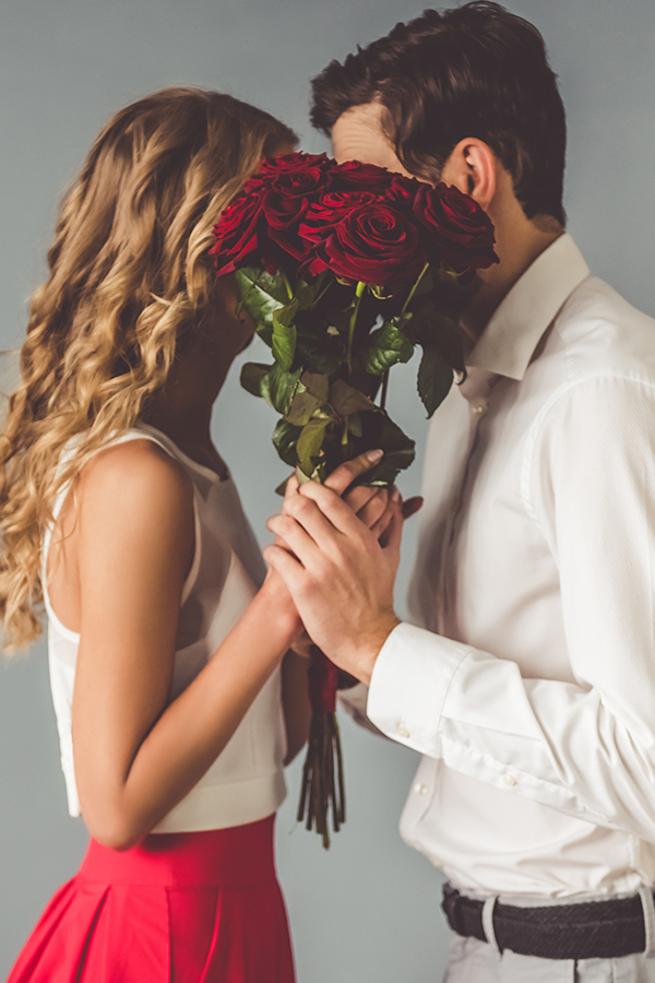 A couple cuddling behind a bunch of roses