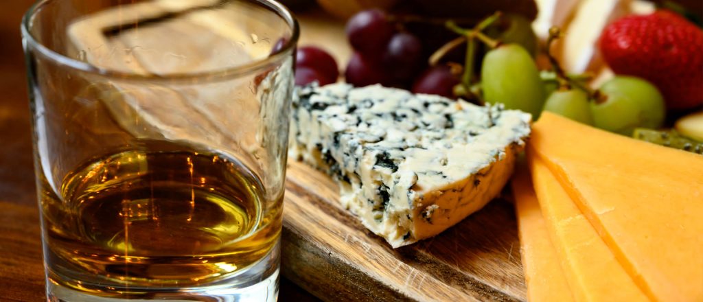 A glass of whisky next to a cheese board