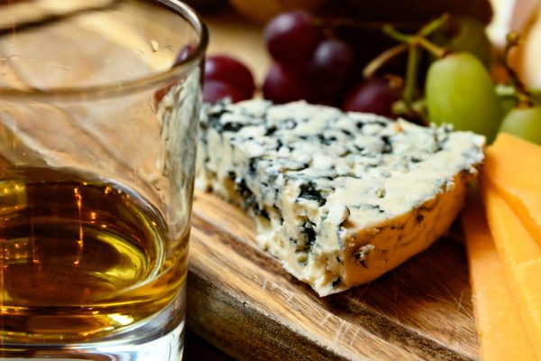 A glass of whisky next to a cheese board