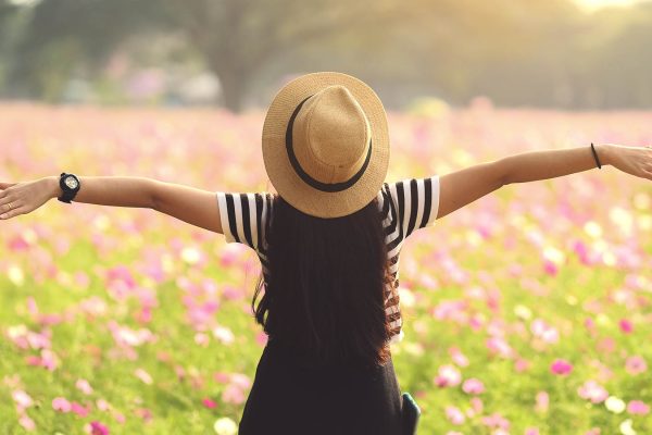 A girl in front of a field full of flowers with her arms outstretched