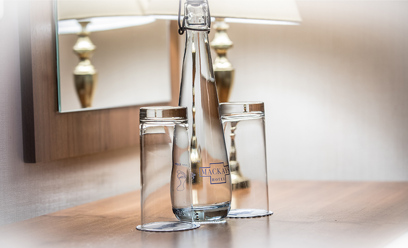 A bottle of water and glasses in a double room at Mackays Hotel in Wick