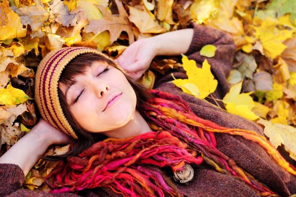 A girl relaxing and lying amidst Autumn leaves