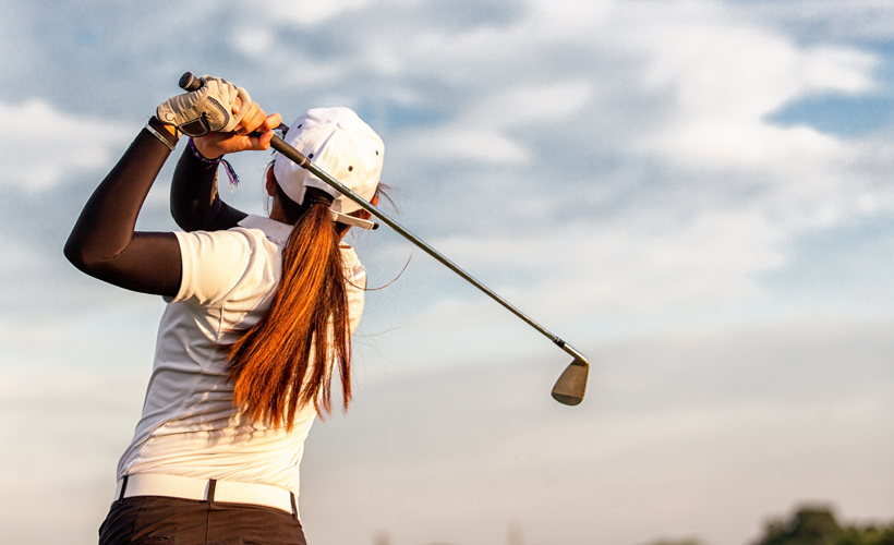 View of golfer taking a swing against a blue sky