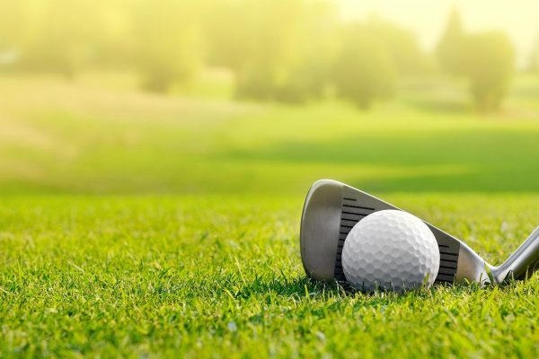 Golf ball and club on green grass