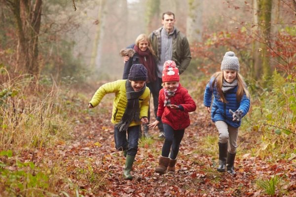 A family enjoys a winter walk with autumn leaves on a forrest path