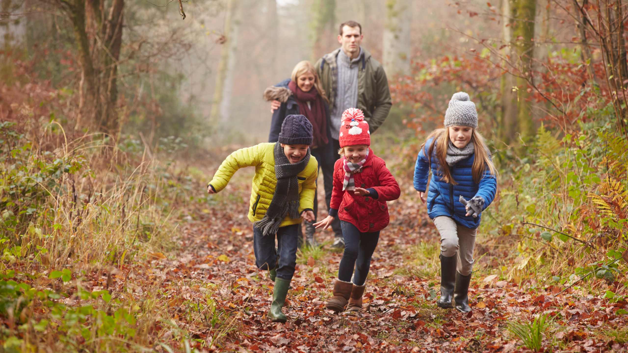 A family enjoys a winter walk with autumn leaves on a forrest path