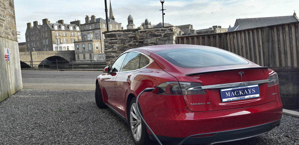 A red electric Tesla car charging at Mackays Hotel in Wick