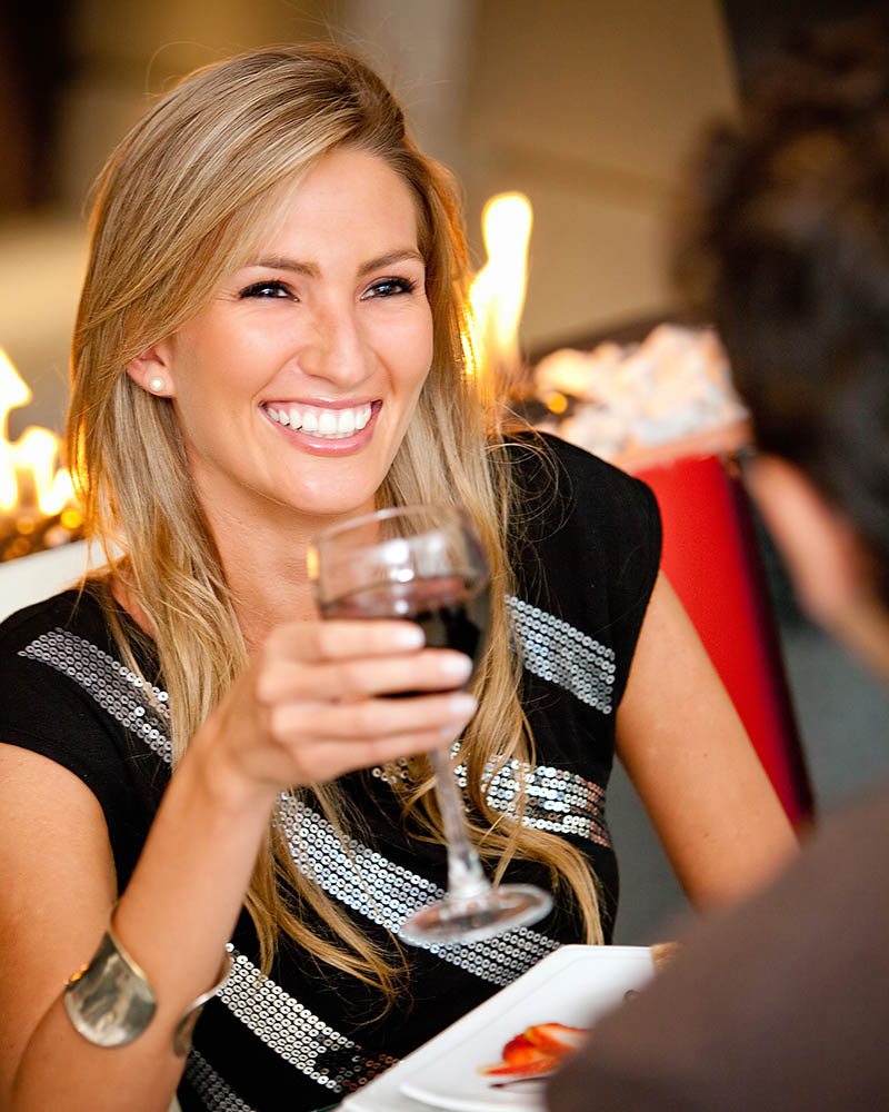 A woman smiling and having a glass of wine