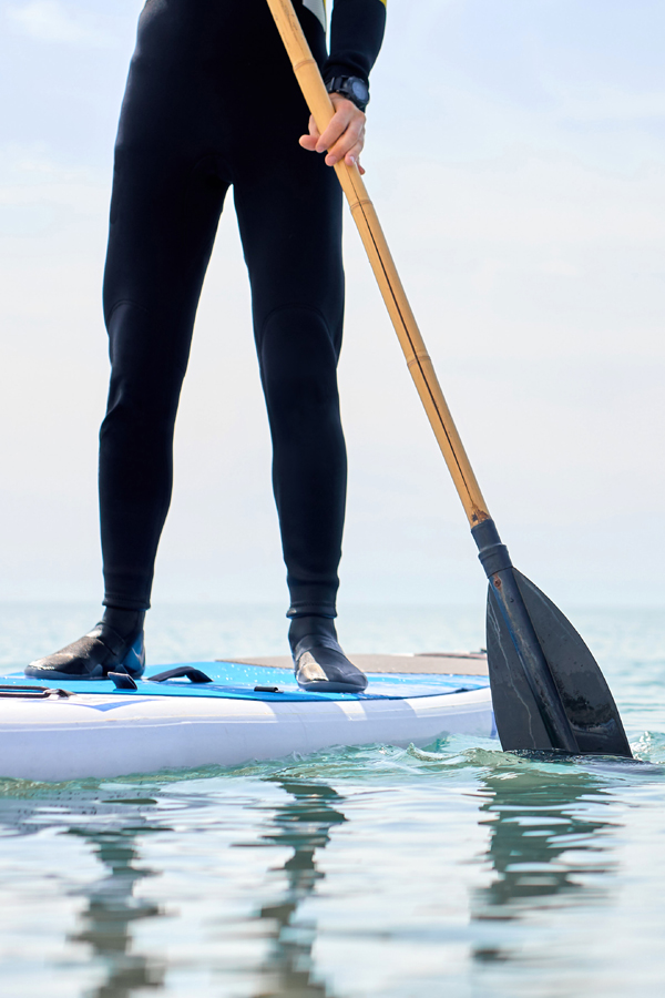 Man in wetsuit stand up paddleboarding