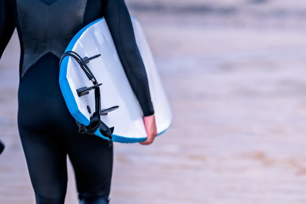 Surfer walking along the beach with board