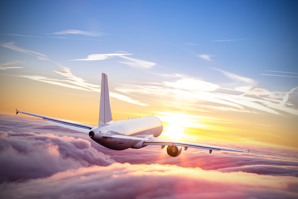 Aeroplane flying above clouds in dramatic sunset light