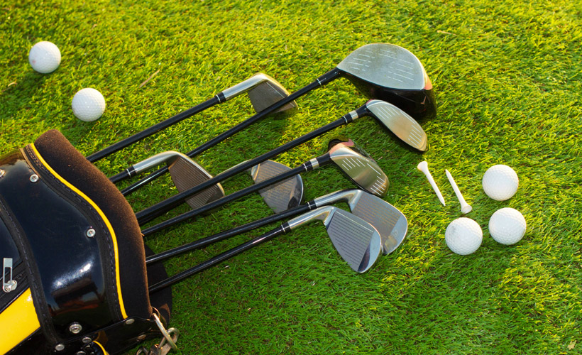 Golf clubs, balls and tees laid out on the green