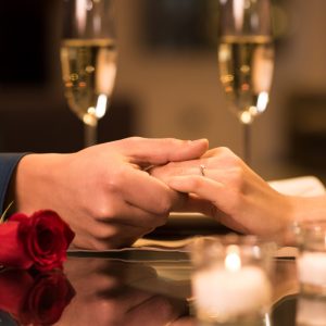 Holding hands at dinner table with champagne