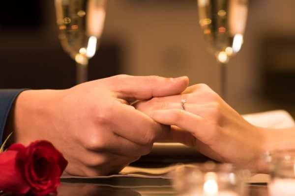 Holding hands at dinner table with champagne