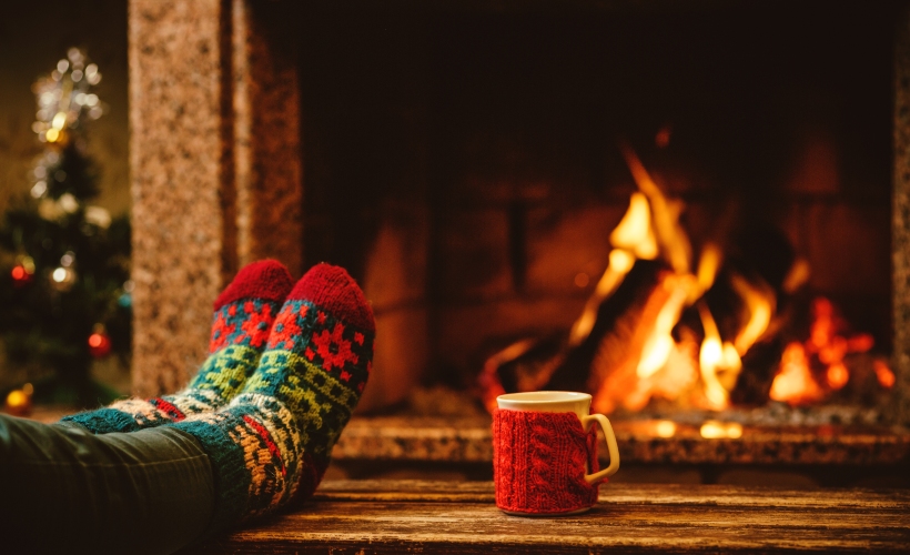 Legs up on table with wooly socks and a cup of hot chocolate in front of the fire