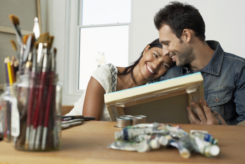 Happy young couple looking at painting in artist studio