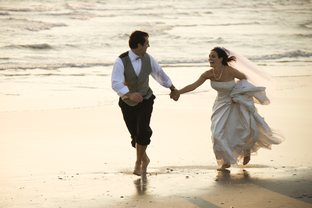 Bride and groom running on a beach