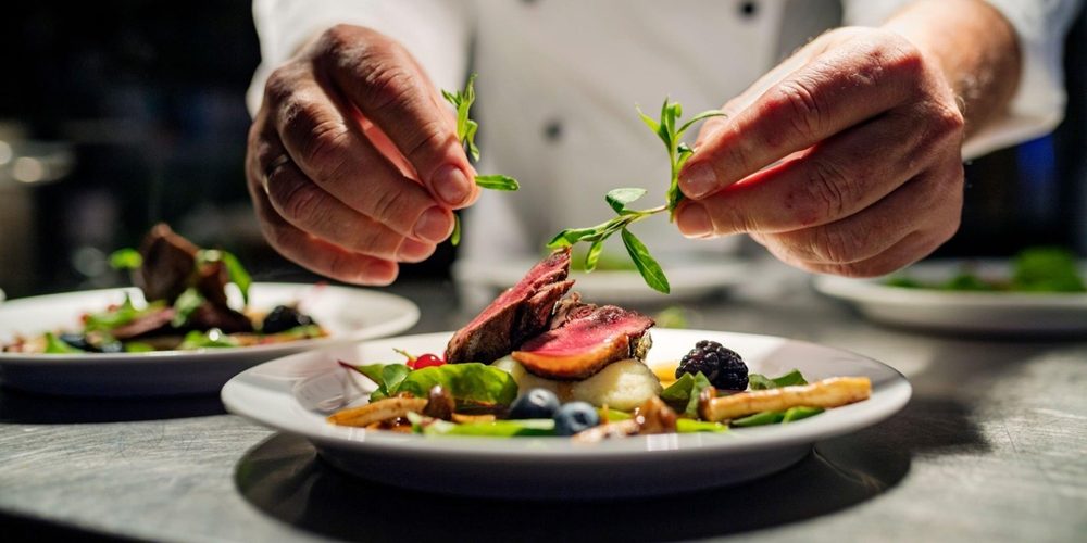 A chef plating up Fine dining cuisine.