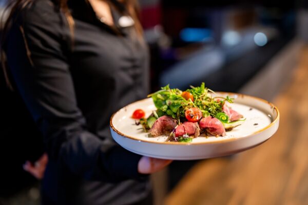 Person holding a plate of gourmet salad with seared tuna. The image captures the art of fine dining and beautifully presented dish.
